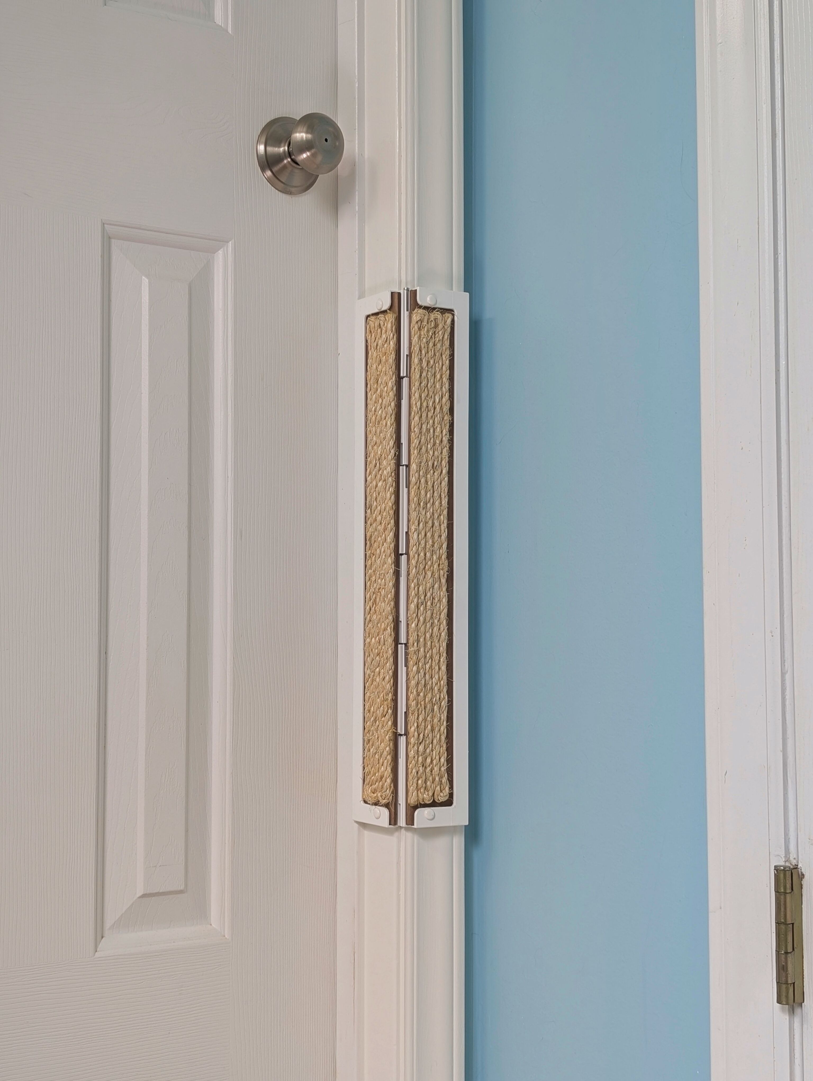 Close-up of a a white door frame with a sisal Jack's Scratcher installed and a light blue wall