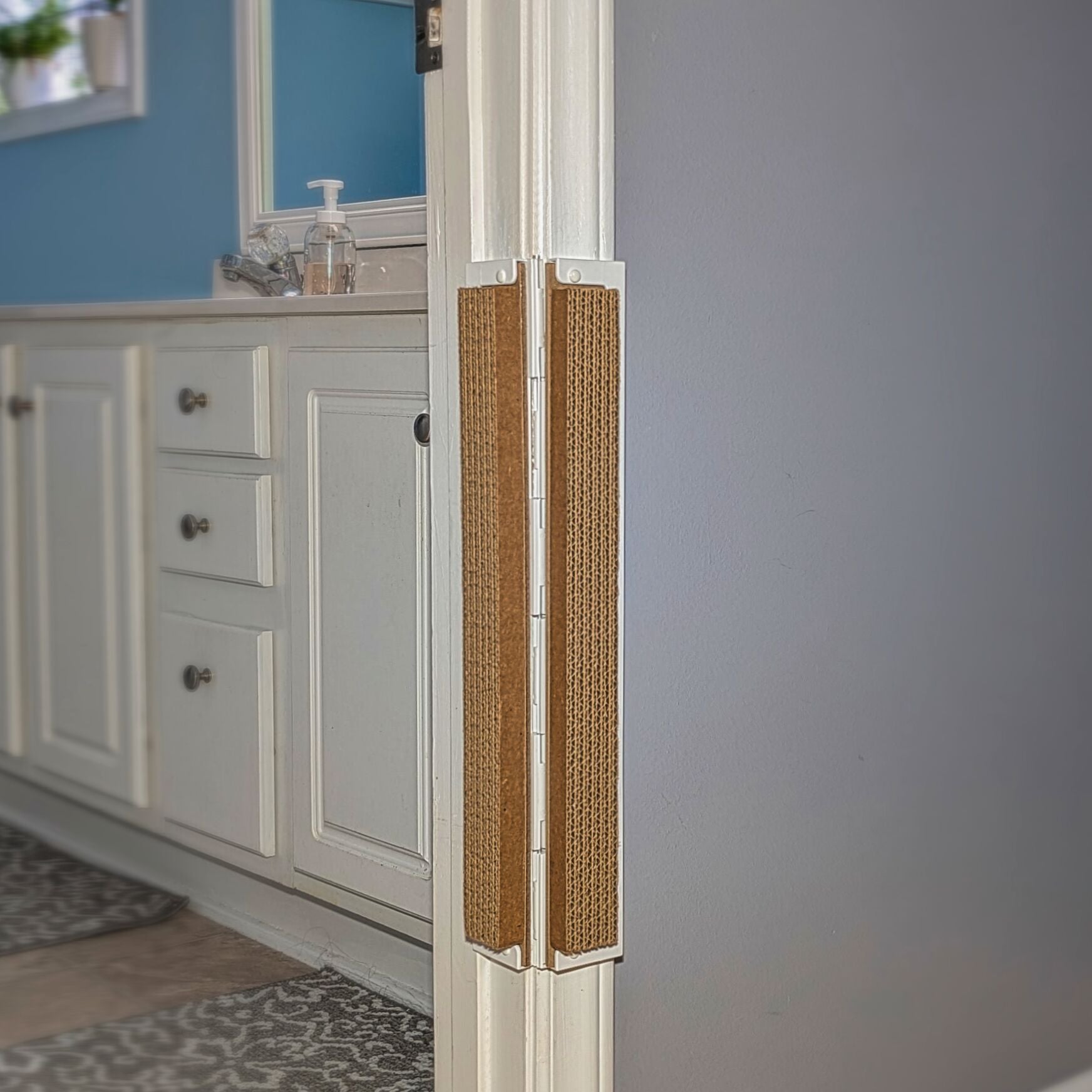 Bathroom with white cabinets, a sink, and a blue  wall and Jack's Scratcher installed on the door frame.