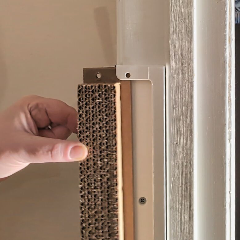 Hand sliding a cardboard insert into a Jack's Scratcher frame.  