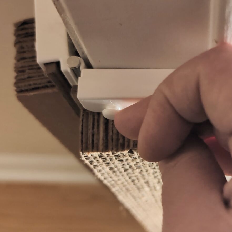 Close-up of a hand removing a locking pin from the Jack's Scratcher frame.