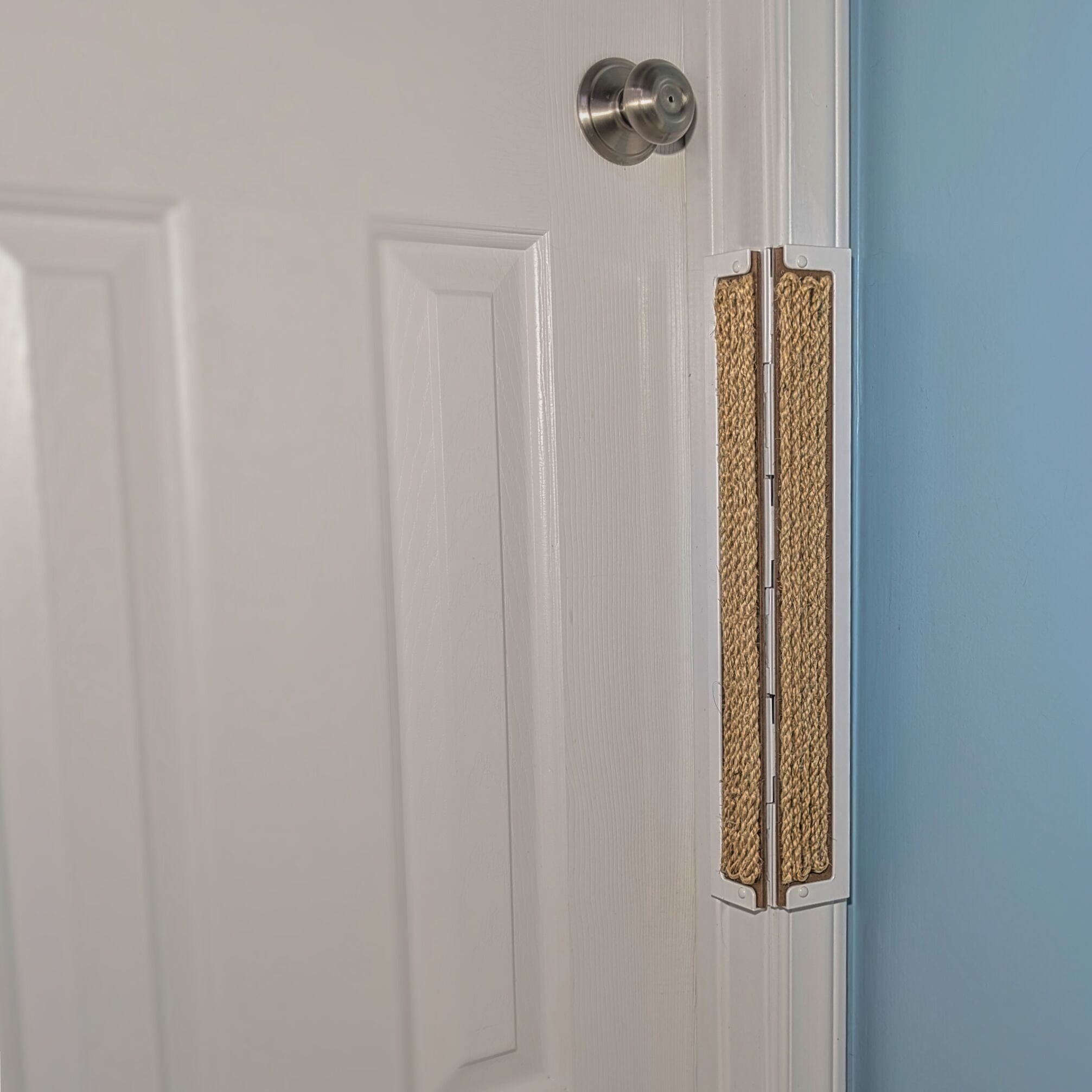 Sisal Jack's Scratcher installed on a white door frame with a white door and blue wall.